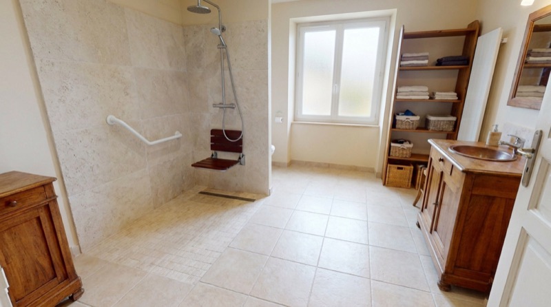 Douche de plain-pied équipée d’une barre d’appui et d’un siège rabattable